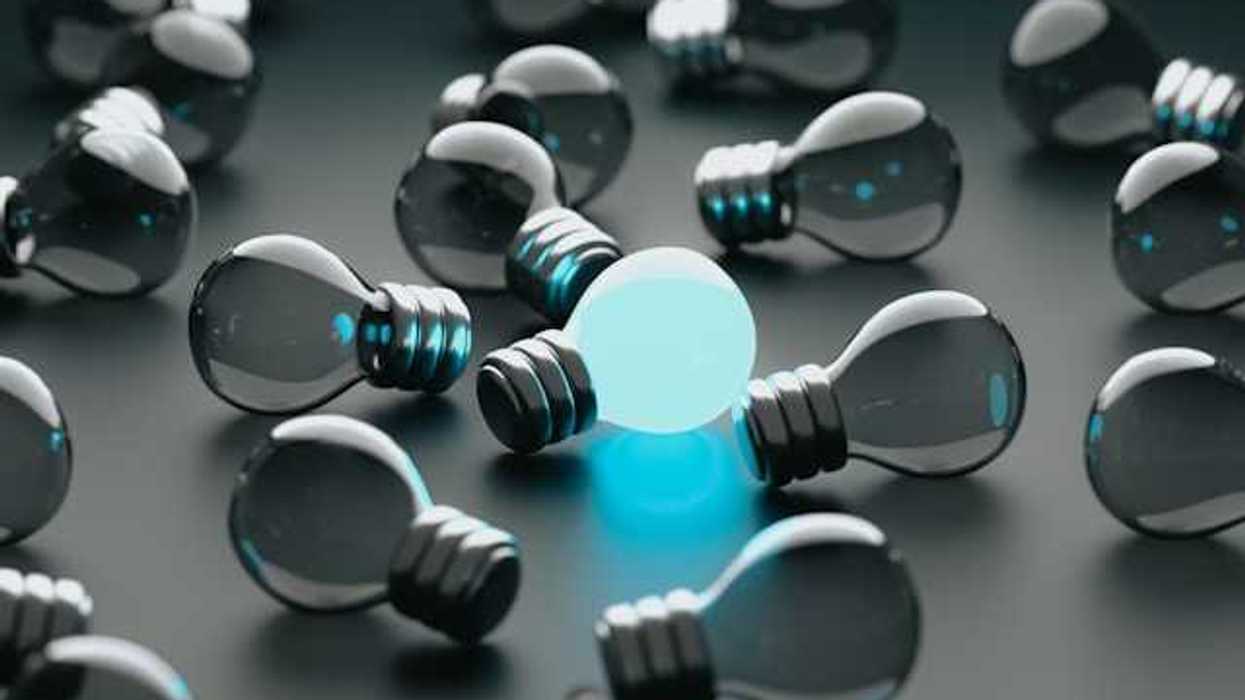 A group of unlit lightbulbs with one bulb glowing blue