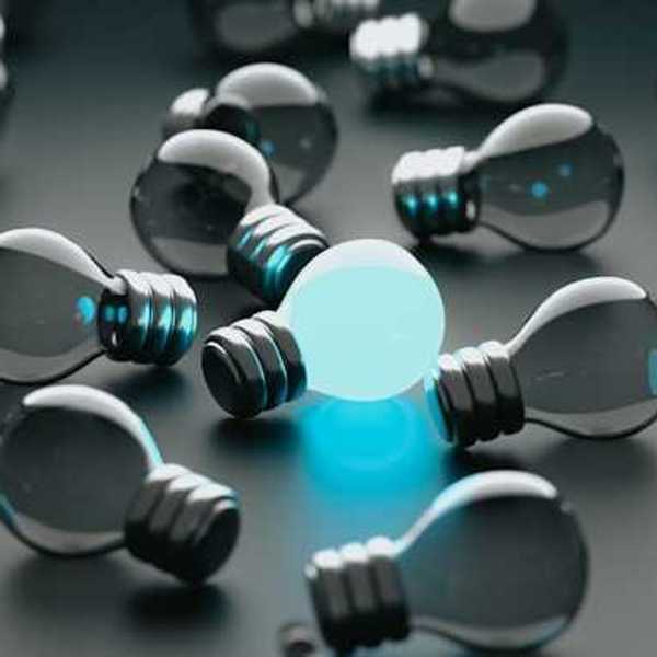 A group of unlit lightbulbs with one bulb glowing blue