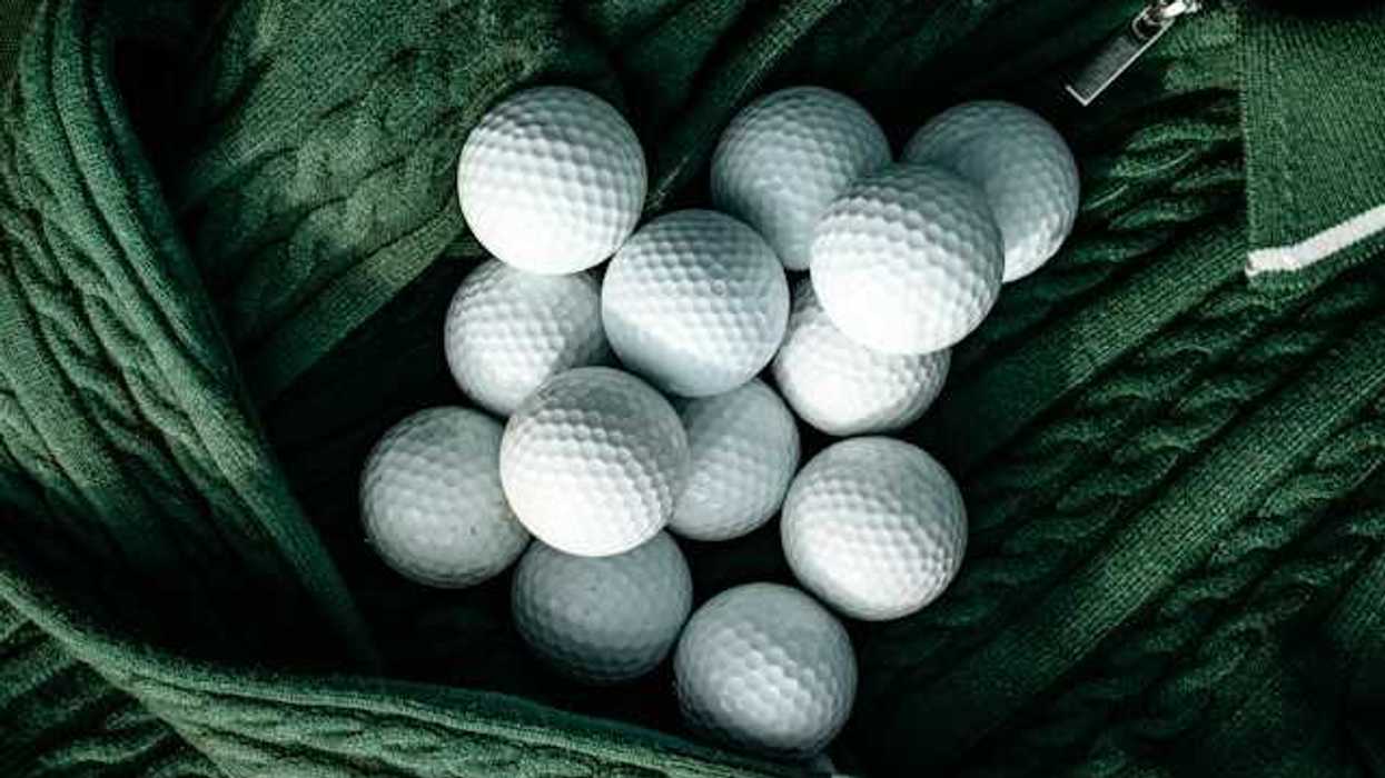A group of white golf balls nestled in a green sweater