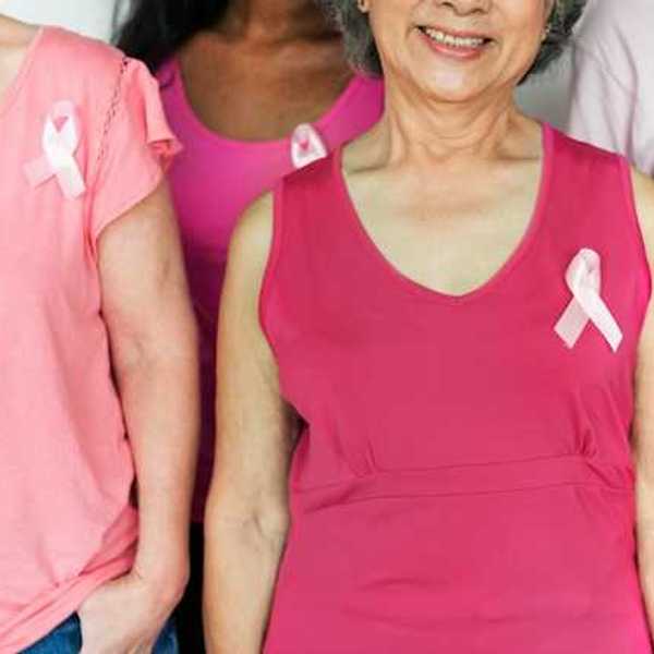 A group of women with pink shirts and breast cancer awareness pins on