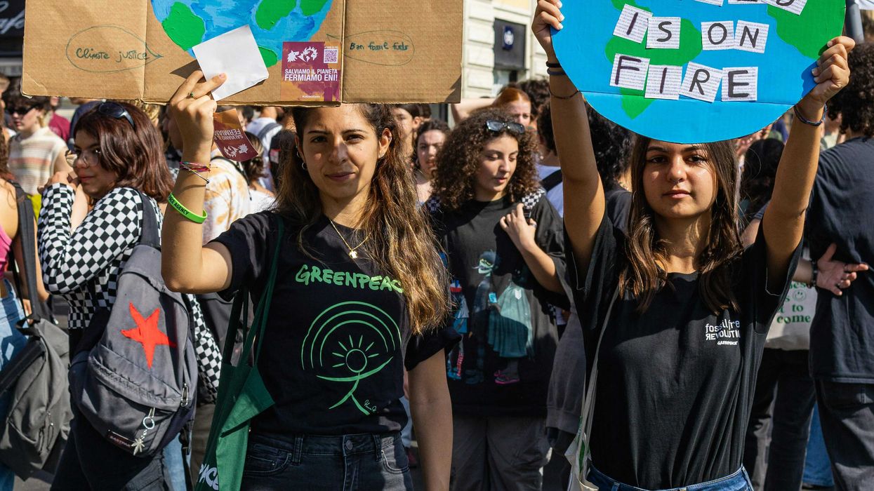 a group of young people holding up climate protest signs in the street.