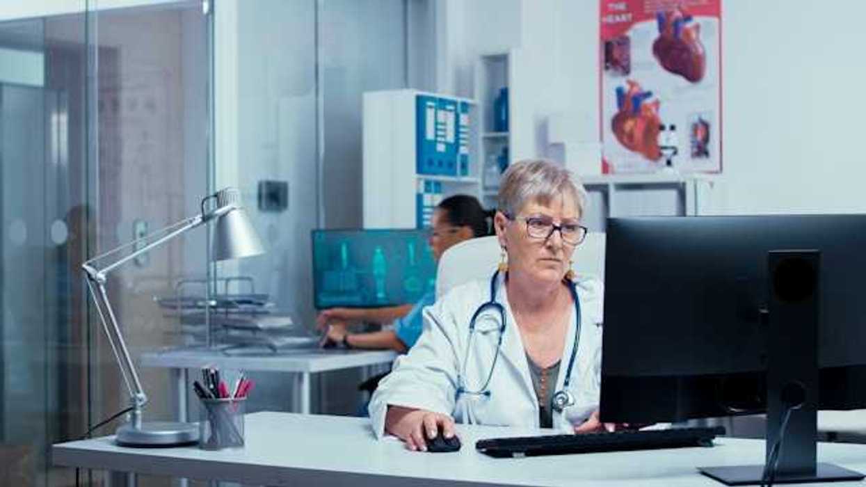 A health professional sitting at a computer in a medical clinic