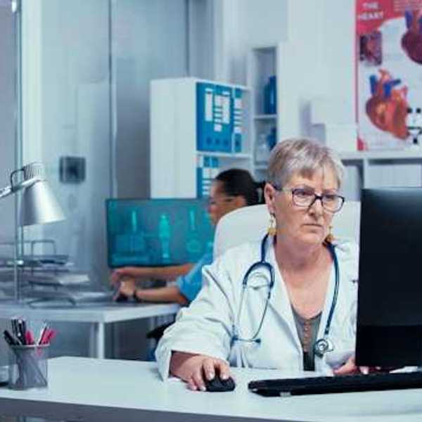 A health professional sitting at a computer in a medical clinic