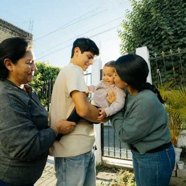 A hispanic family in their courtyard playing with a baby