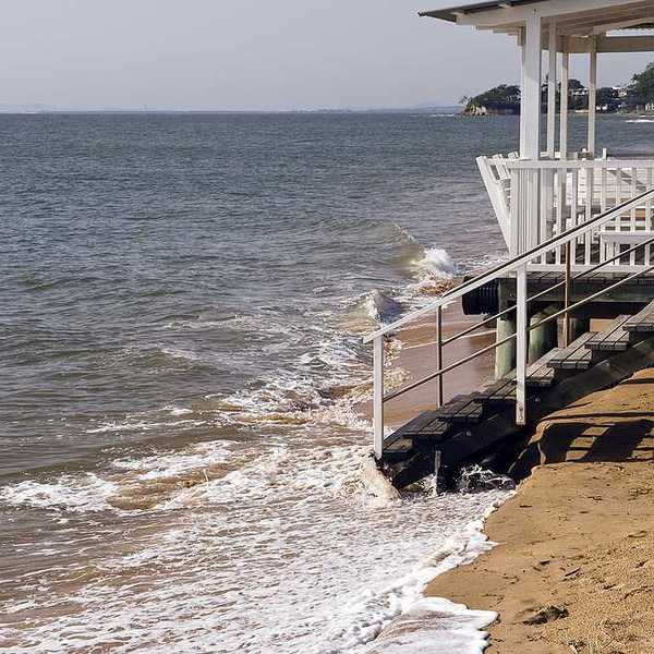 A home on a beach that is being inundated by sea water