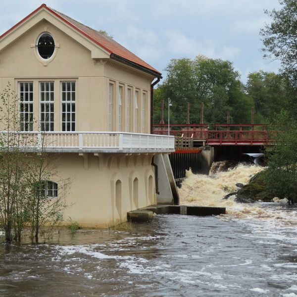 a house on a flooded street with a bridge in the background