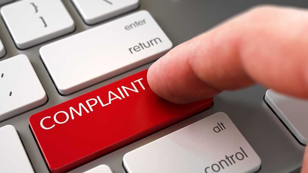 A keyboard showing a red Complaint button with a finger pressing it