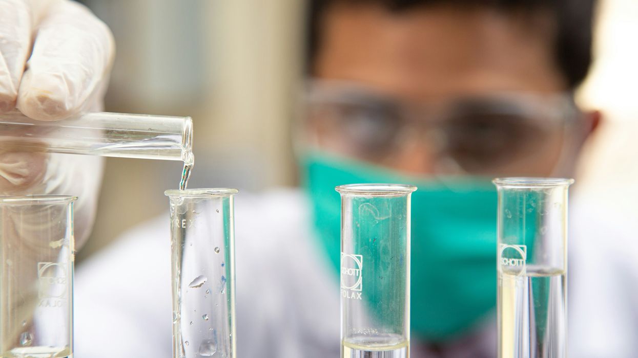 A lab tech works with testubes