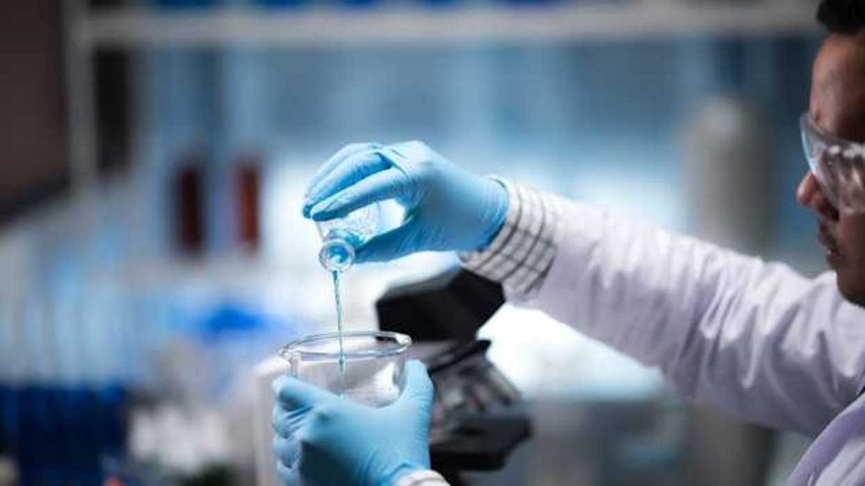 A lab worker pouring blue liquid into a beaker