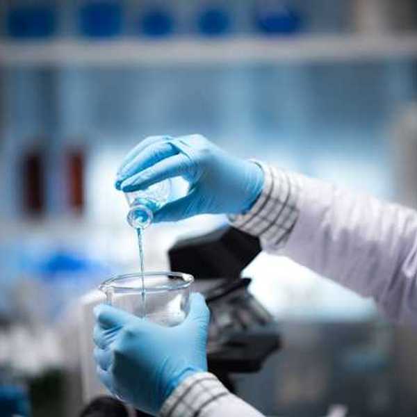 A lab worker pouring blue liquid into a beaker