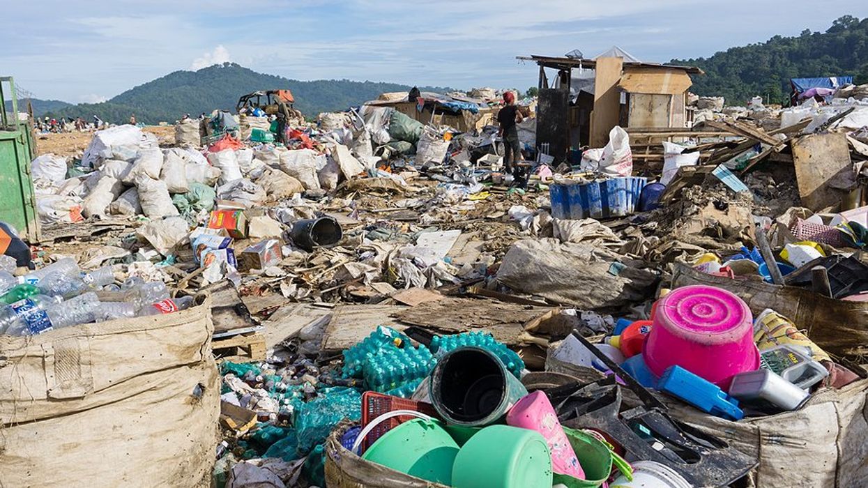 A landfill with piles of plastic waste being collected.
