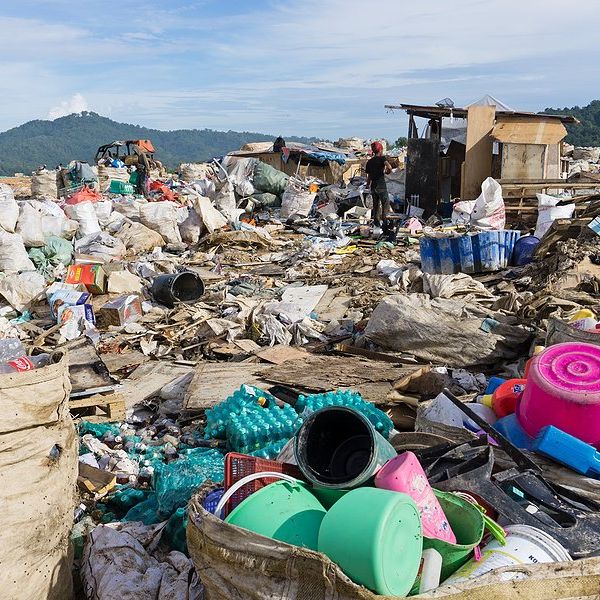 A landfill with piles of plastic waste being collected.