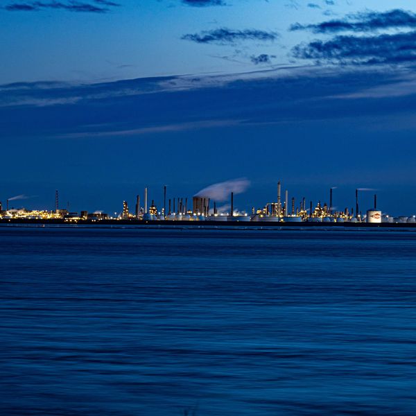 A large body of water with a refinery complex in the background.
