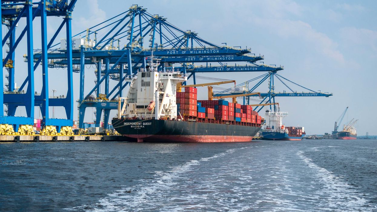 a large cargo ship in the water with a large crane in the background.