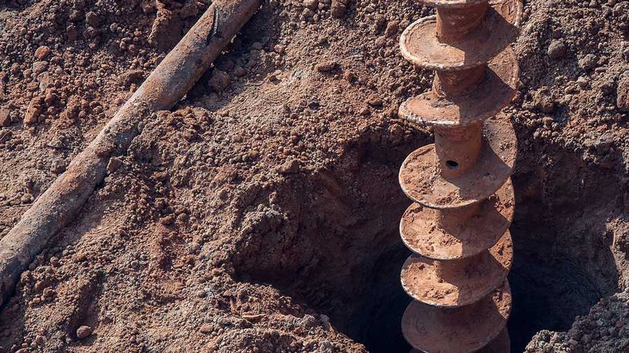 A large drill making a hole in dry earth