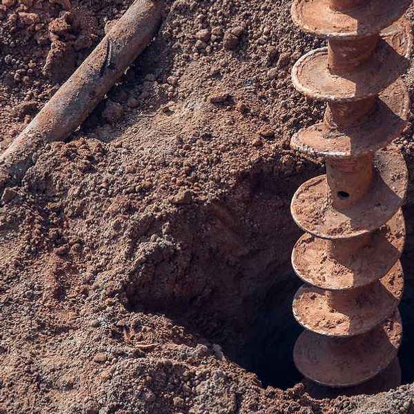 A large drill making a hole in dry earth