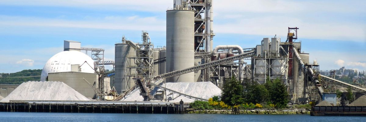 a large factory building next to a body of water.