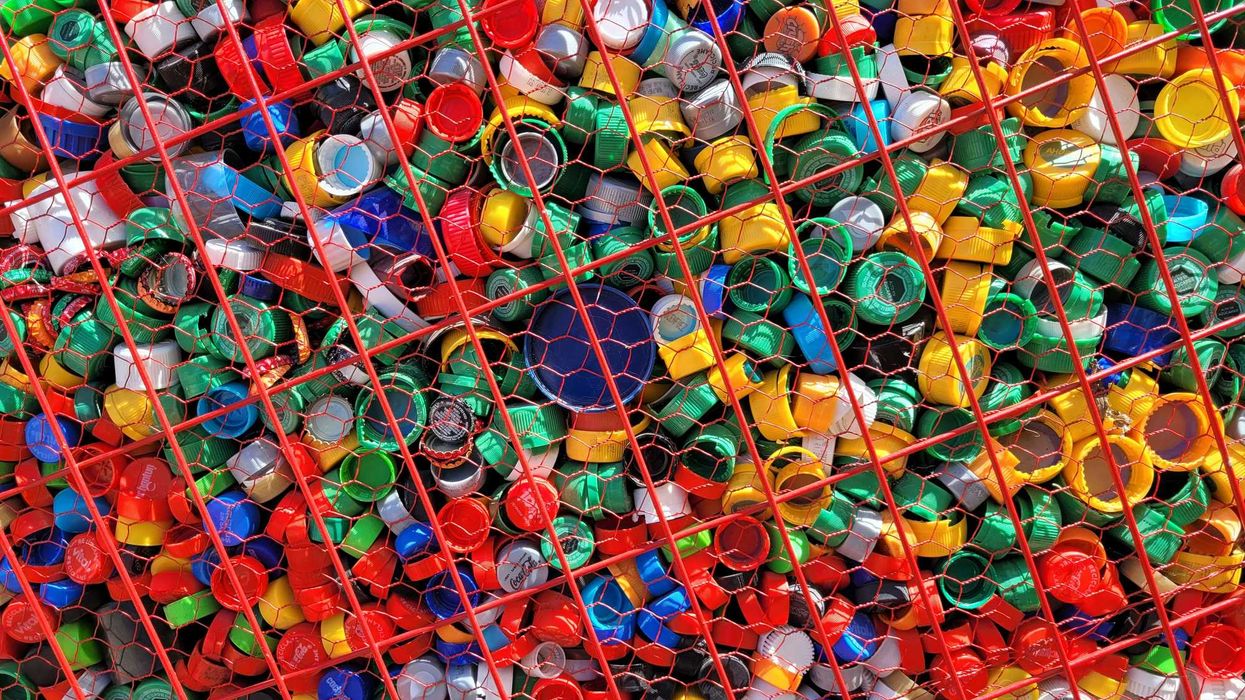a large number of multicolored plastic bottle caps in a wire bin