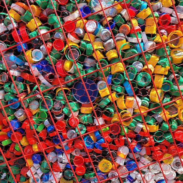 a large number of multicolored plastic bottle caps in a wire bin
