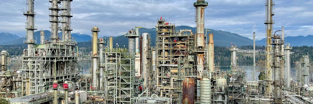 A large oil refinery with mountains in the background.
