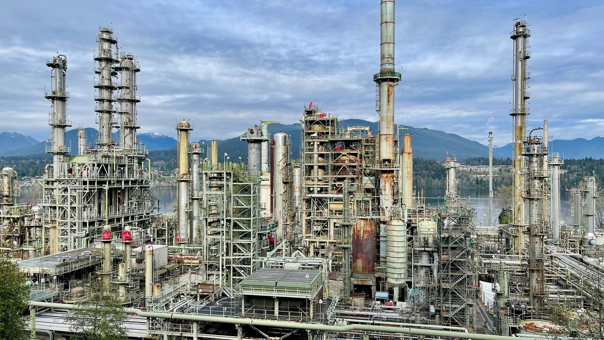 A large oil refinery with mountains in the background.