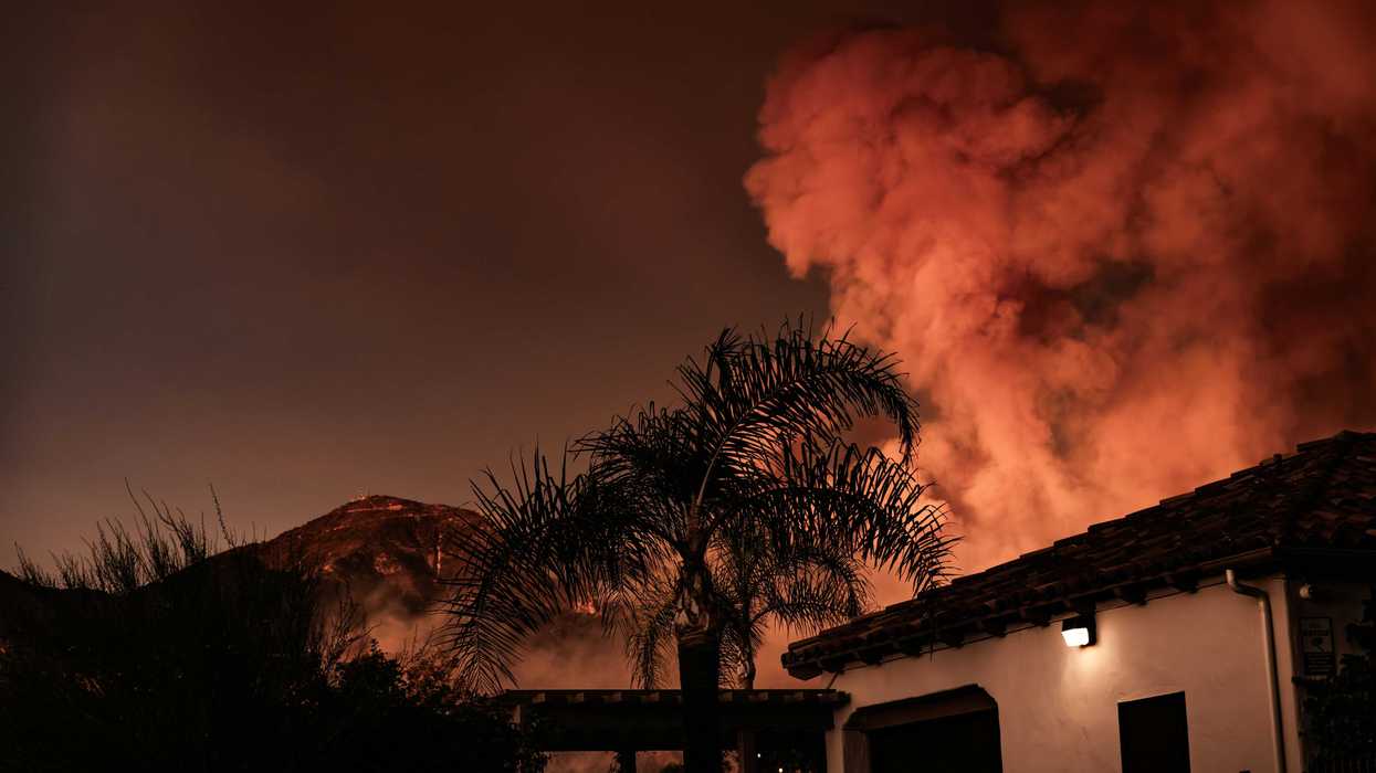 A large plume of smoke billowing behind a building
