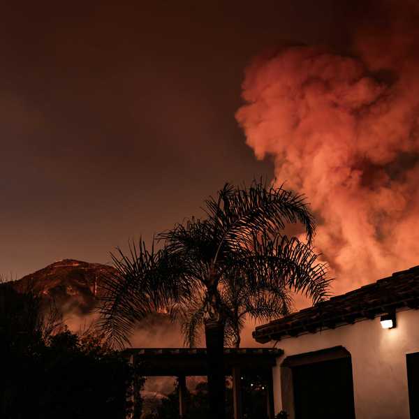 A large plume of smoke billowing behind a building