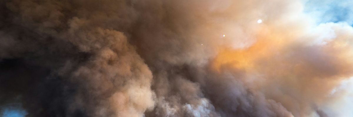A large plume of smoke from a wildfire billows into the sky.