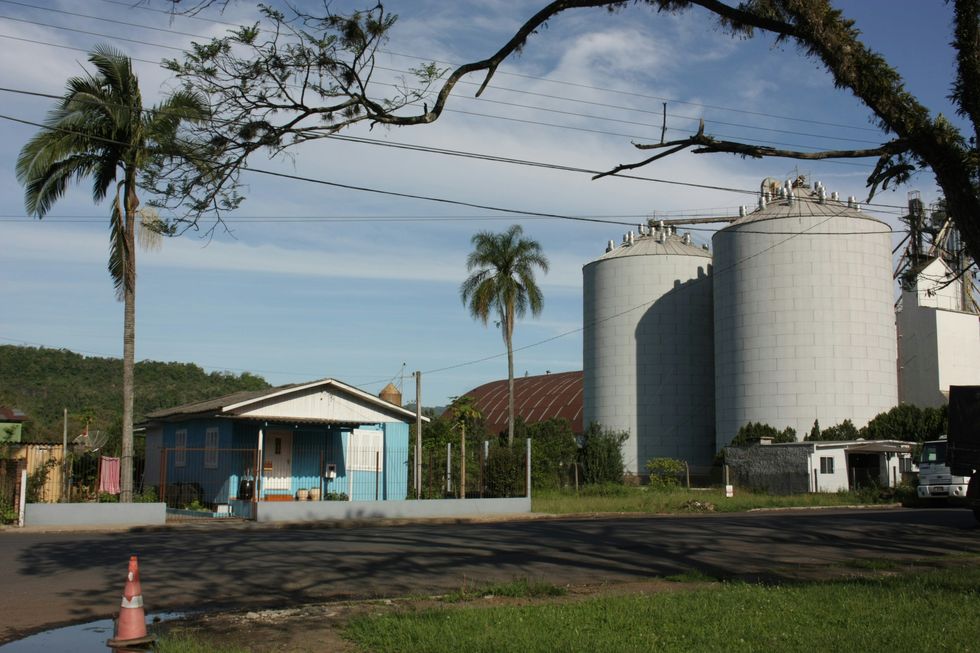 A large white building sitting next to a palm tree and large storage tanks.