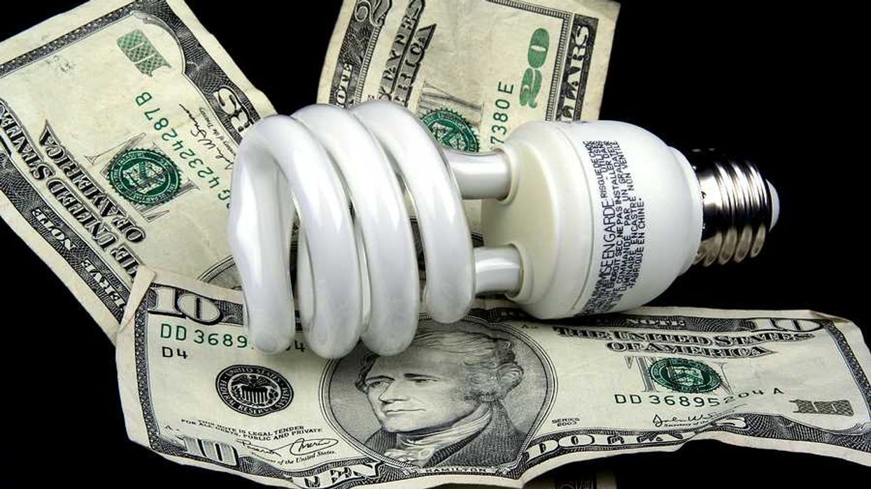 A lightbulb sitting on top of U.S. bills