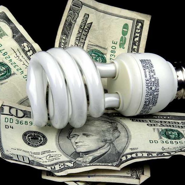 A lightbulb sitting on top of U.S. bills
