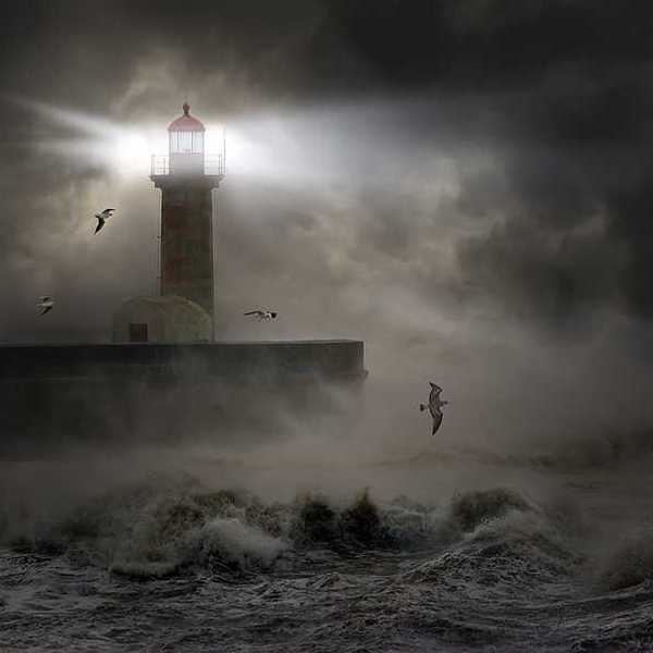 A lighthouse at the end of a promontory during a strong storm