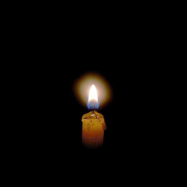 a lit candle in the middle of a dark room.