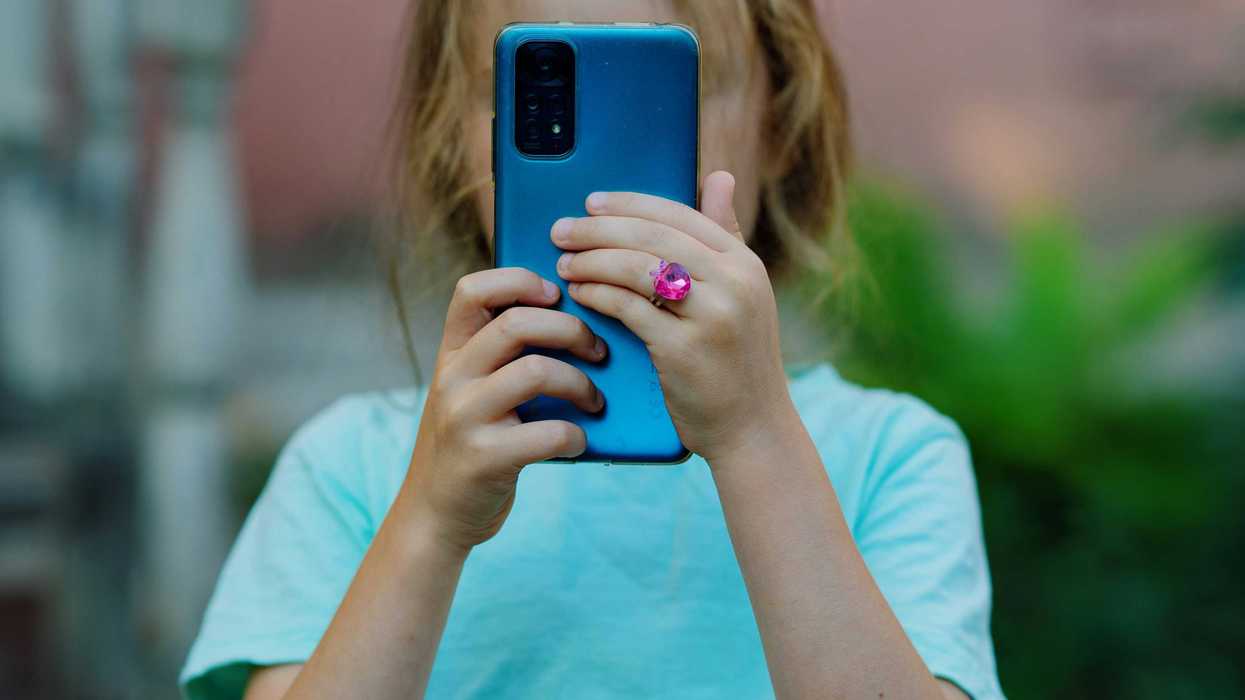 a little girl taking a picture with her cell phone