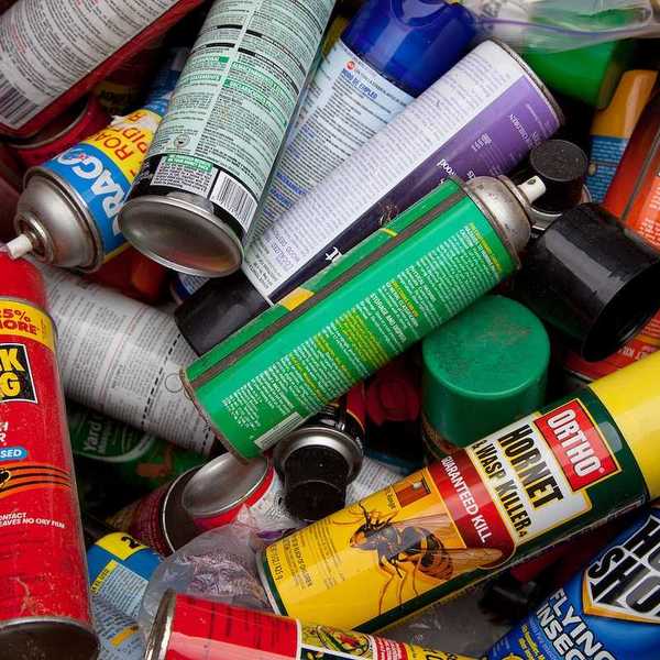 A load of bug spray aerosols lying in a heap at a recycling facility, awaiting processing and recycling