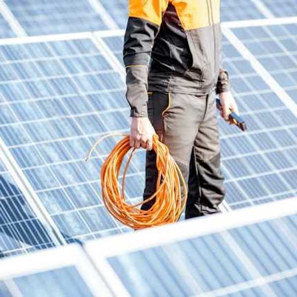 A maintenance worker wearing black standing in front of solar panels