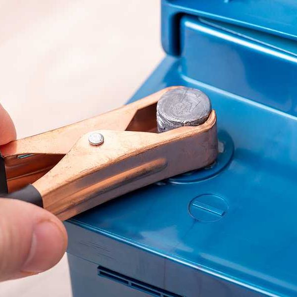 A male hand tightening a bolt on a car battery