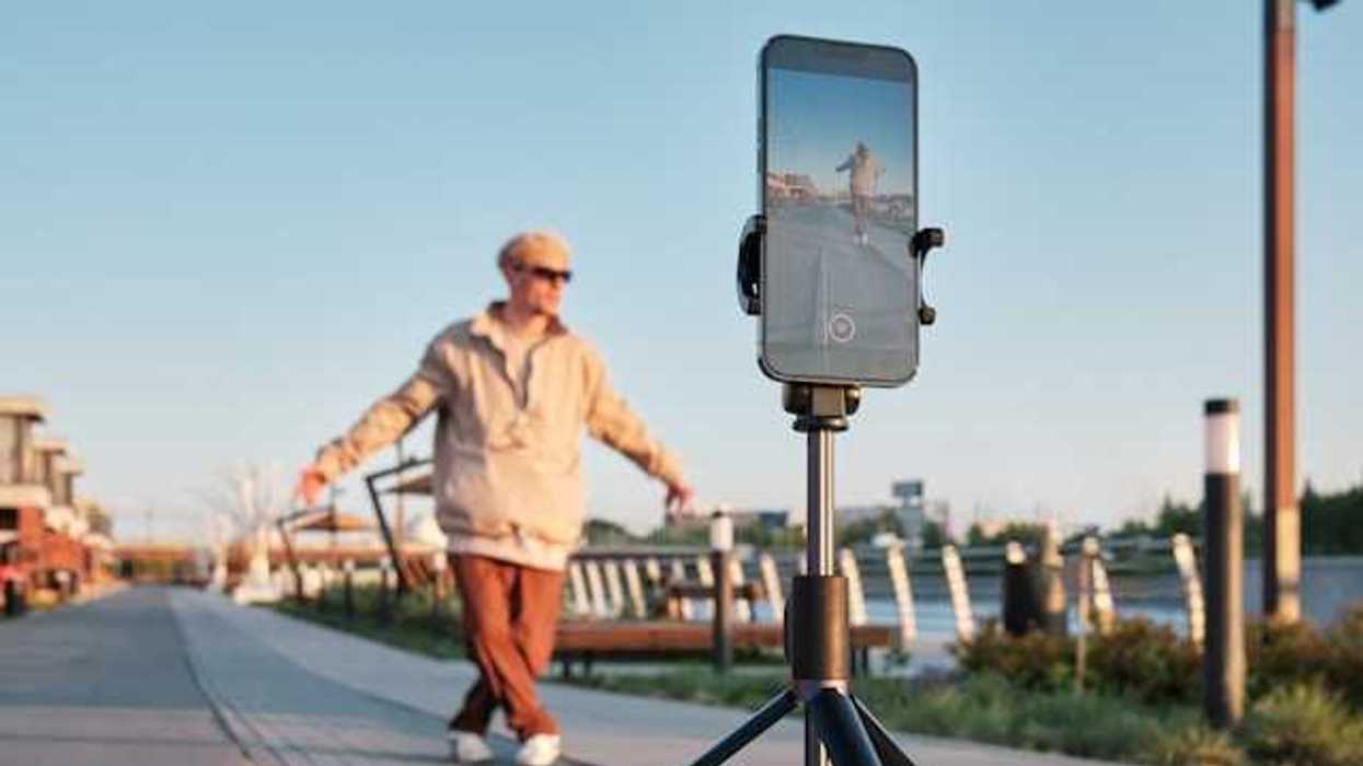 A male influencer standing in front of his phone on a tripod shooting a video
