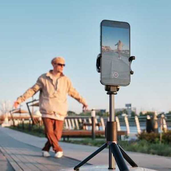 A male influencer standing in front of his phone on a tripod shooting a video