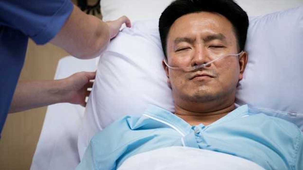 A male patient in a hospital bed with an oxygen tube in his nose