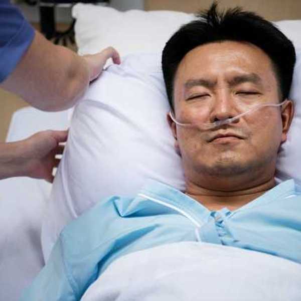 A male patient in a hospital bed with an oxygen tube in his nose