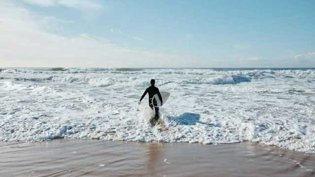 A male surfer walking into the ocean