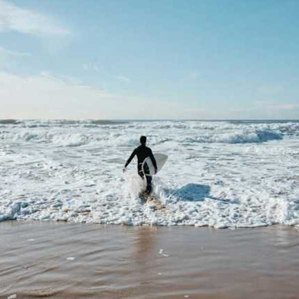 A male surfer walking into the ocean