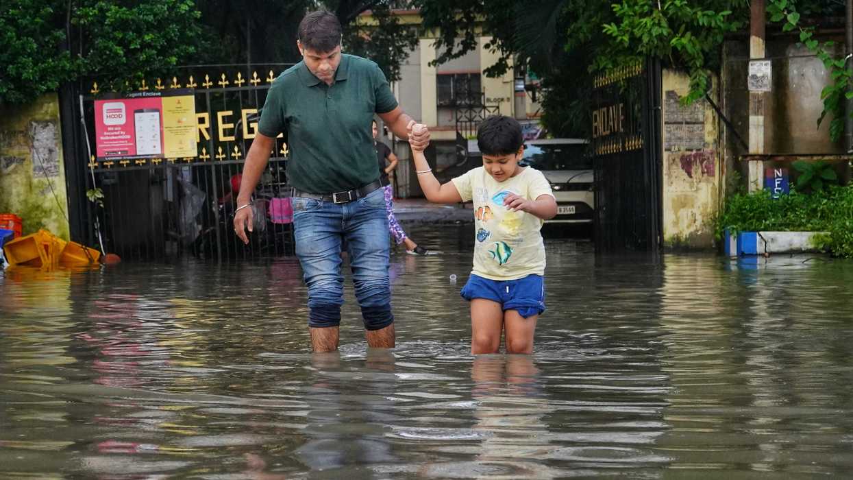a man and a little girl walking through a flooded street.