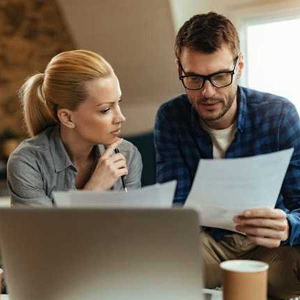 A man and woman at home looking at bills