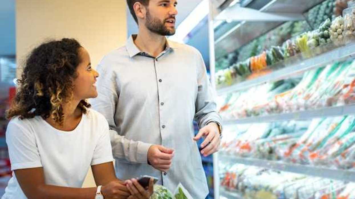 A man and woman in a grocery store looking at produce