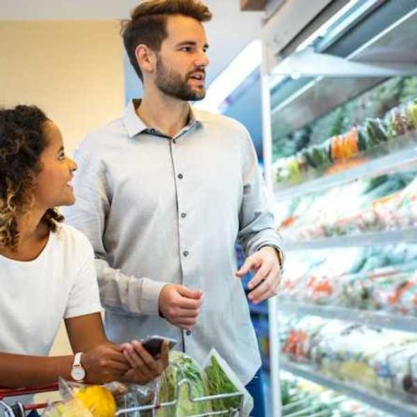 A man and woman in a grocery store looking at produce