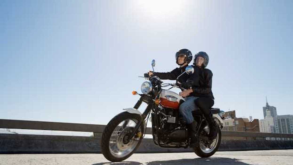 A man and woman riding on a motorcycle on a city street