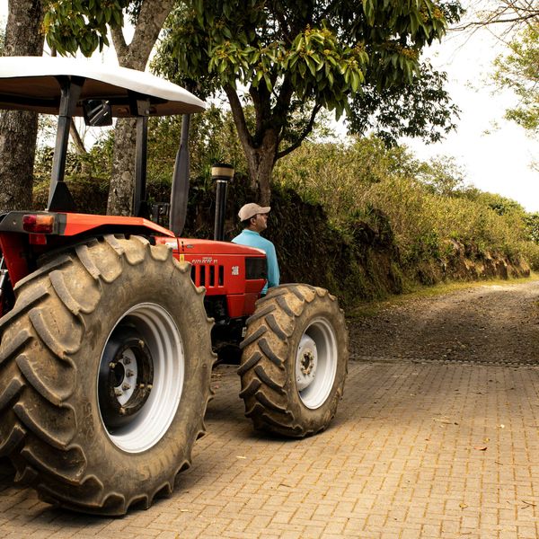 A man driving a tractor down a dirt road.