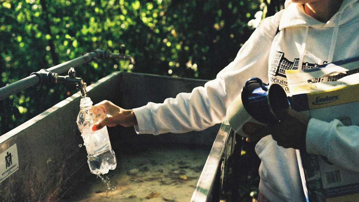 A man filling a water bottle with water holding scientific equipment.